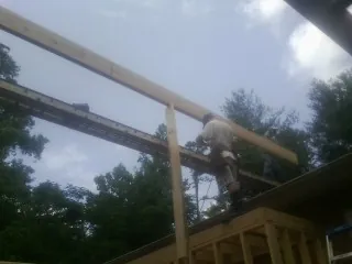 Carpenter setting a ridge beam over a new addition frame — Ice Dam Removal by Roofing Brothers in Moville