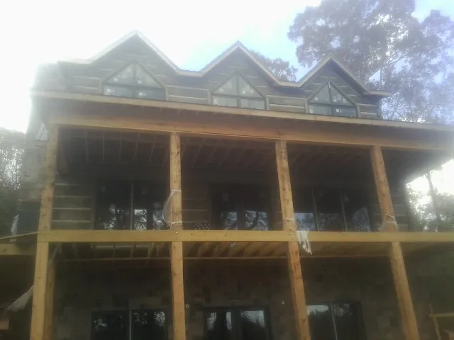 Dormers and porch framing on a large log home under construction — Roof Coating work by our crew in Moville