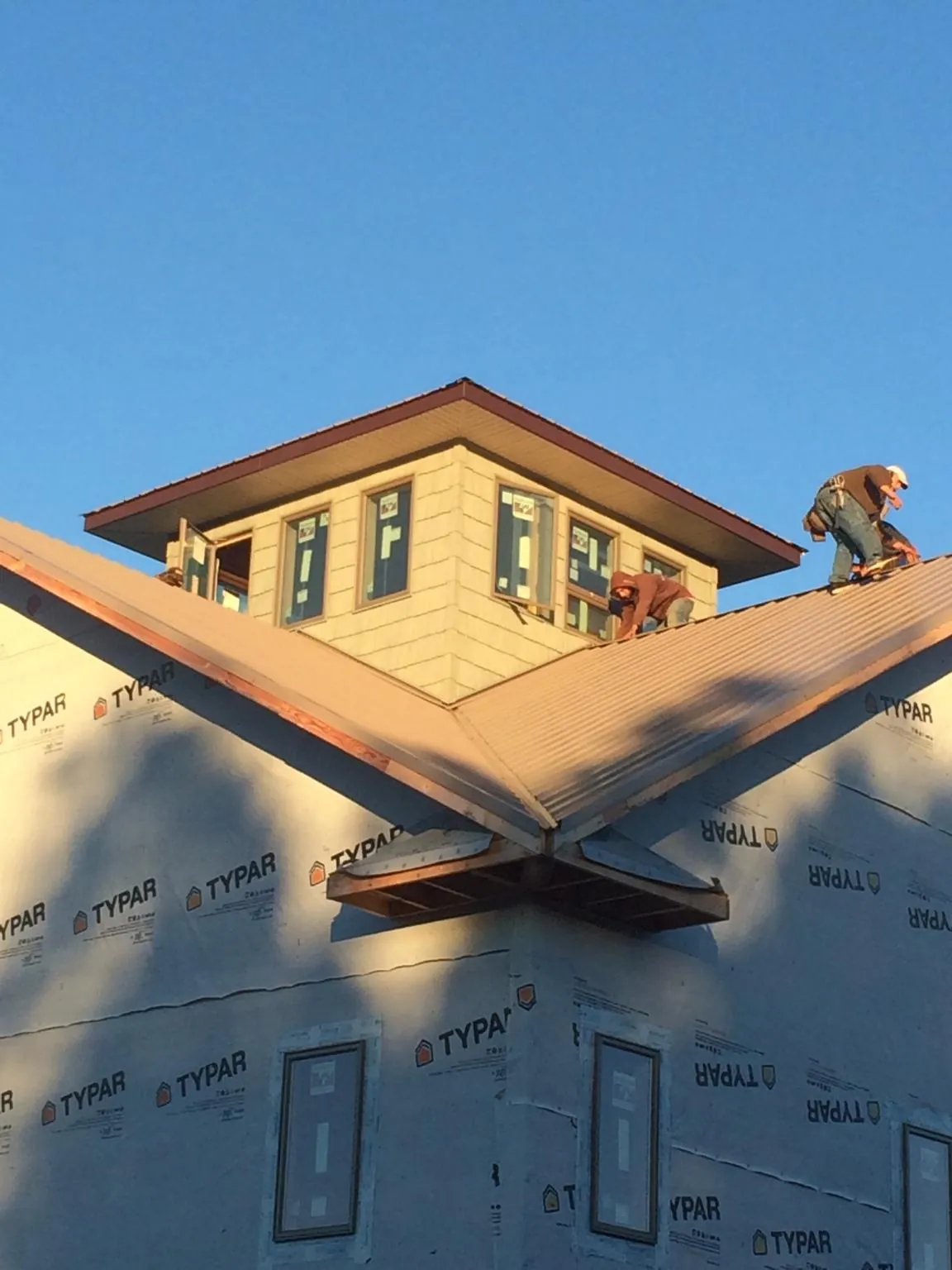 Roofers working around a rooftop cupola on a new metal roof at sunset — Roof Waterproofing in Moville by Roofing Brothers